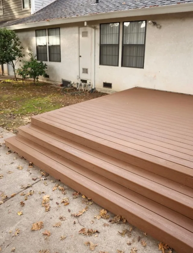 Deck boards and steps finished in a warm tan stain against a stucco wall