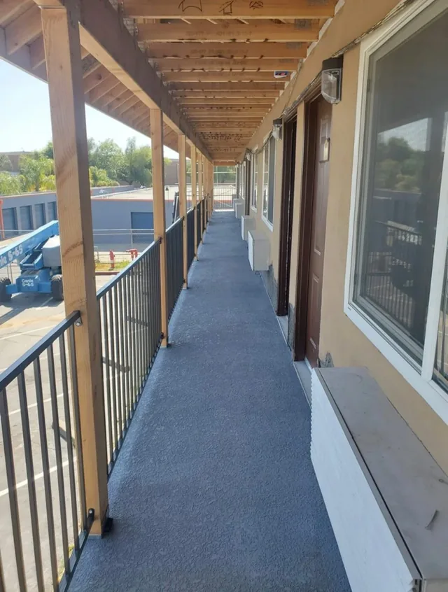 A long covered walkway with painted posts and railing running along a building