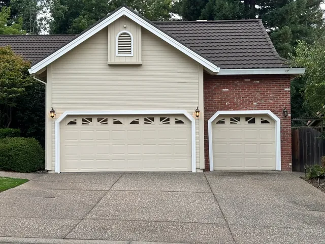 Cream garage doors and trim on a brick and siding home