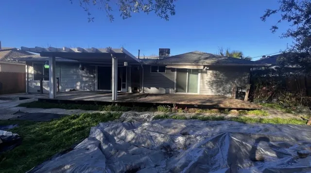 Wide view of a single-story home with a deck and pergola, work in progress