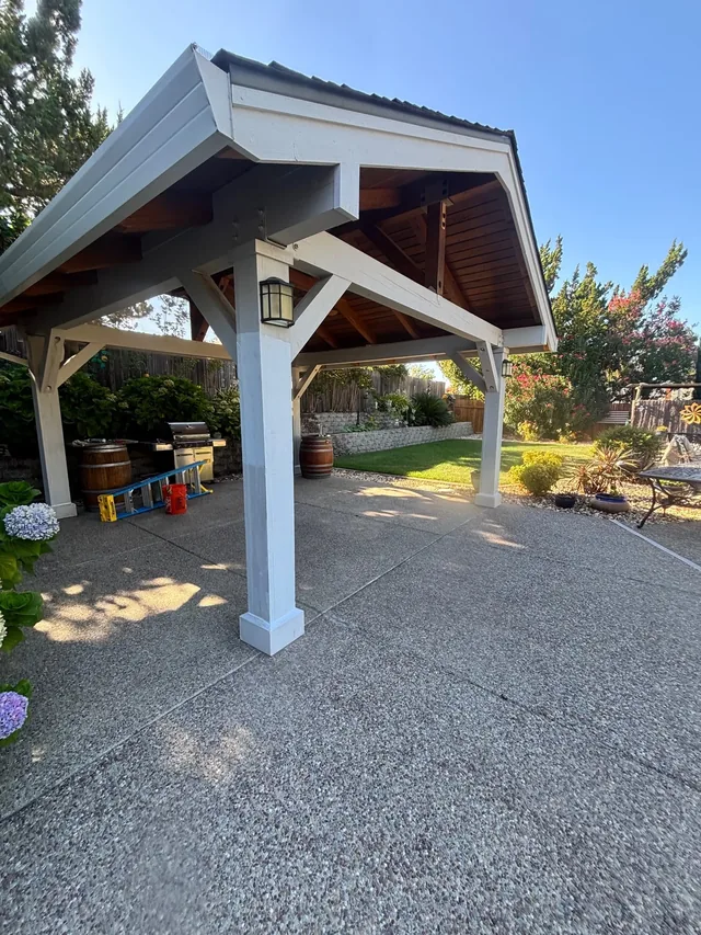 A freestanding pavilion with white painted posts and beams