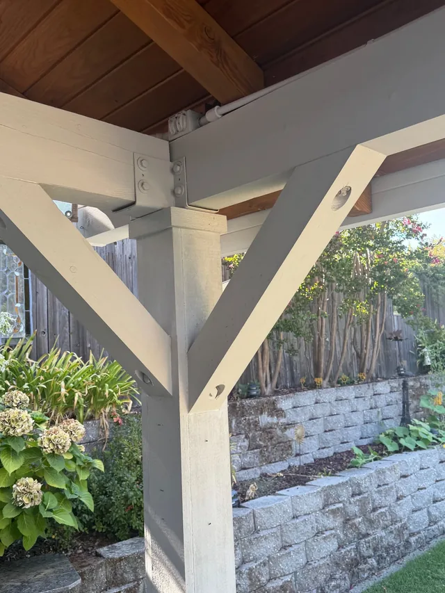 Close view of a pergola post and angled brace finished in cream